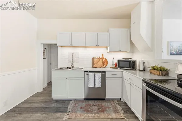 a kitchen with stainless steel appliances a stove a sink and white cabinets