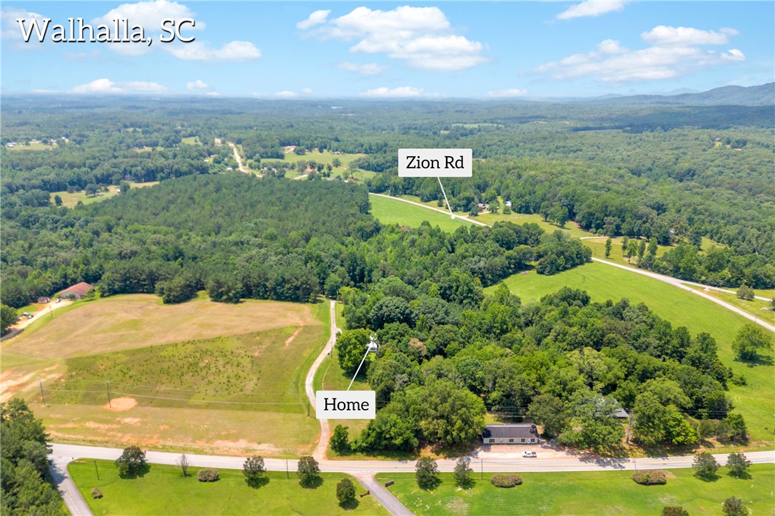 150 Newberry Road Walhalla, SC 29691 - Photo 44 of 47 An aerial perspective reveals the property nestled amidst verdant fields and a dense forest canopy.