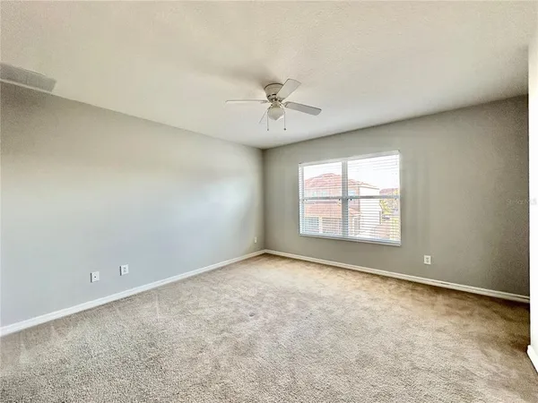 an empty room with a window and a ceiling fan
