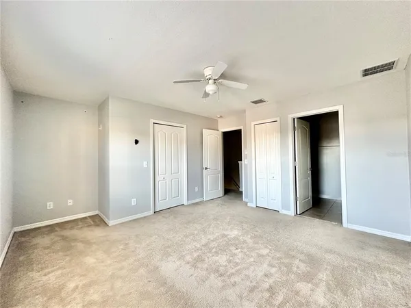 an empty room with closet and a ceiling fan