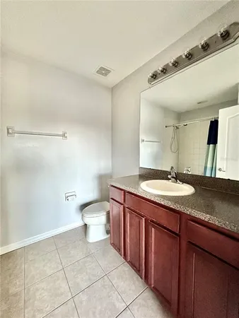a bathroom with a granite countertop sink a toilet and a mirror