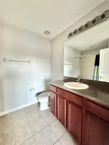 a bathroom with a granite countertop sink a toilet and a mirror