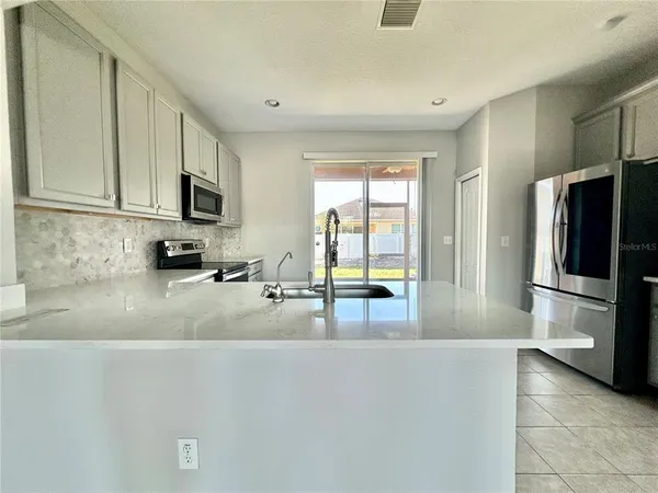 a kitchen with stainless steel appliances a refrigerator a sink a stove top oven a counter space and cabinets