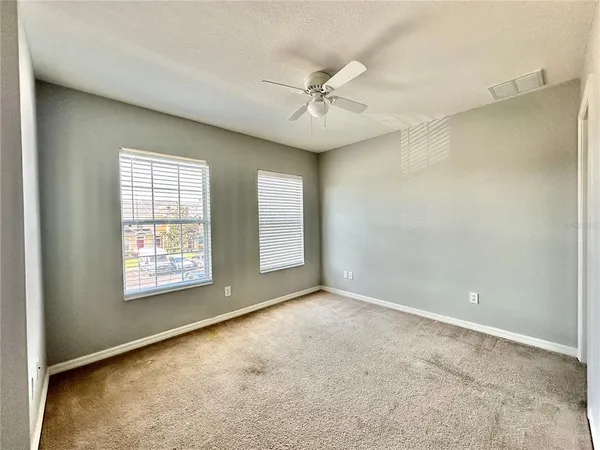 an empty room with windows and fan