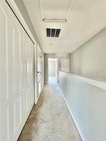 a view of a hallway with white walls and stairs