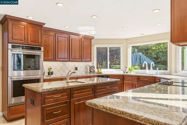 a kitchen with stainless steel appliances granite countertop a refrigerator and a wooden cabinets