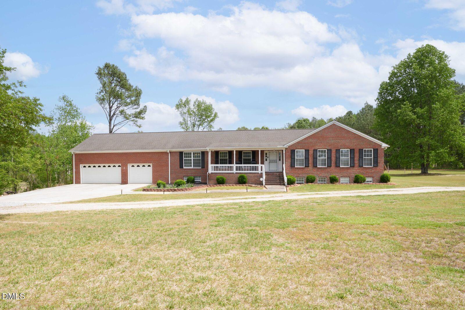 a front view of house with yard and trees in the background