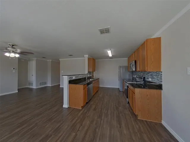 a kitchen with stainless steel appliances granite countertop a stove a sink dishwasher and a refrigerator with wooden floor