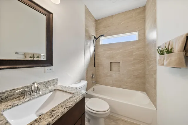 a bathroom with a granite countertop sink a toilet a mirror and shower
