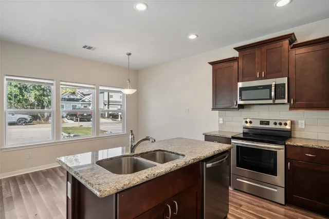 a kitchen that has a sink a stove and microwave