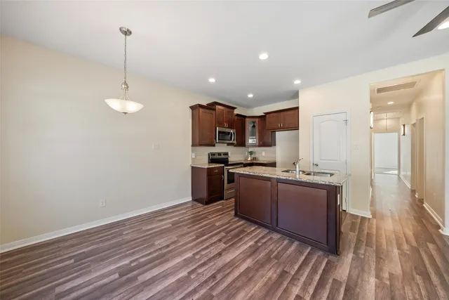 a kitchen with stainless steel appliances granite countertop a refrigerator a sink dishwasher a stove and white countertops with wooden floor