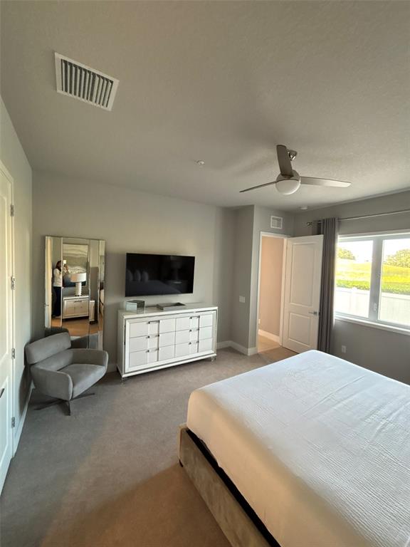 7740 Sandy Ridge Drive, Unit 131 Reunion, FL 34747 - Photo 11 of 27 a bedroom with a bed a couch and a flat screen tv