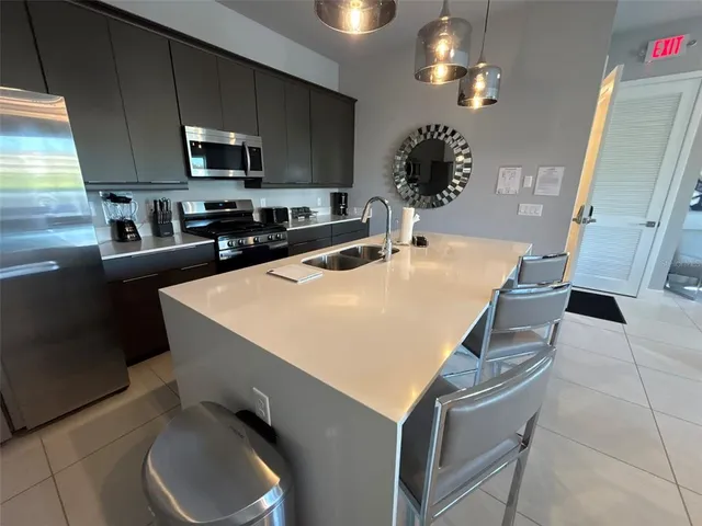 a kitchen with stainless steel appliances a stove a sink a microwave a refrigerator and cabinets