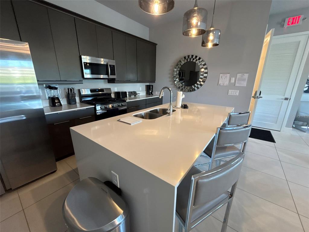 7740 Sandy Ridge Drive, Unit 131 Reunion, FL 34747 - Photo 5 of 27 a kitchen with stainless steel appliances a stove a sink a microwave a refrigerator and cabinets