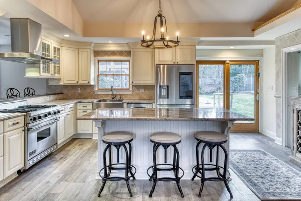 a kitchen with stainless steel appliances a dining table chairs and wooden floor