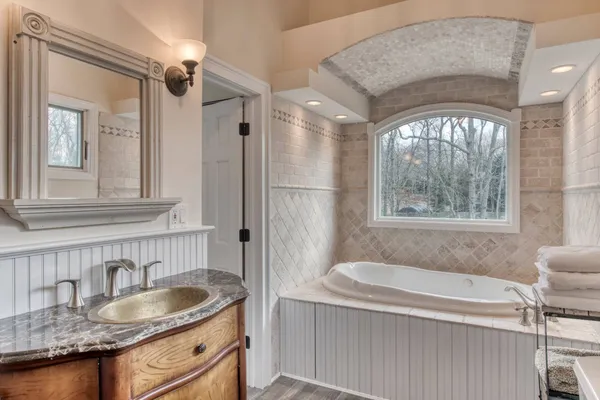 a bathroom with a granite countertop tub sink and mirror
