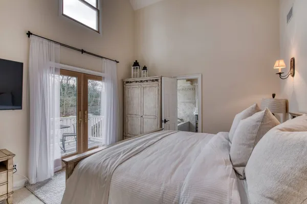 a bedroom with a large bed and a flat tv screen