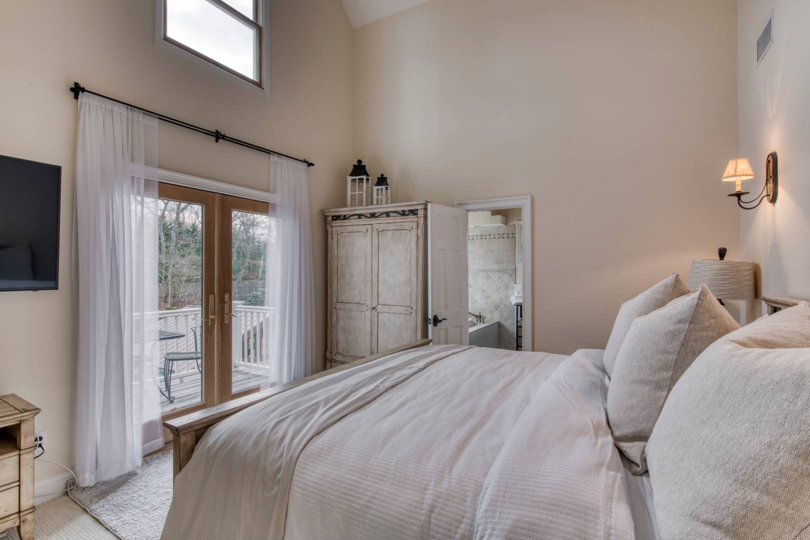 1532 Noyack Road Southampton, NY 11968 - Photo 10 of 15 a bedroom with a large bed and a flat tv screen