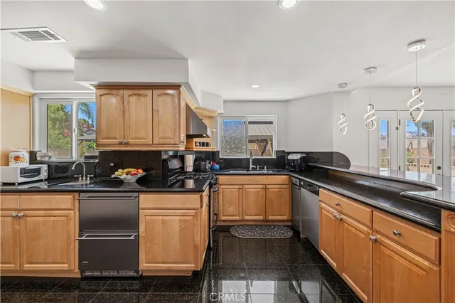 a kitchen with stainless steel appliances granite countertop sink a stove a dining table and chairs with wooden floor