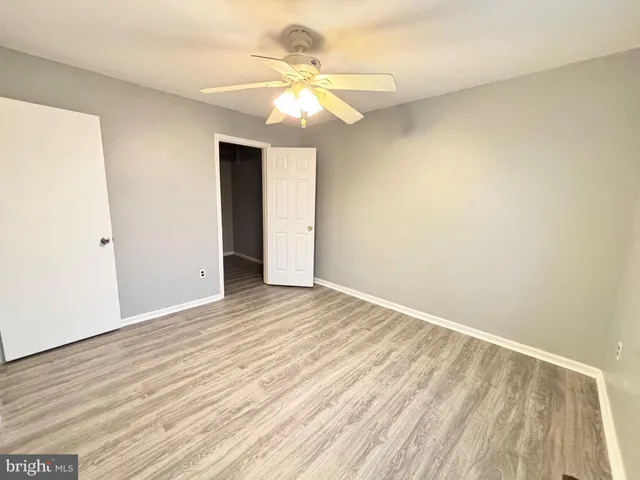 an empty room with wooden floor and fan