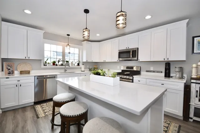 a kitchen with a white center island a stove cabinets and a dining table with wooden floor