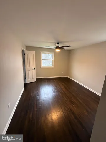 an empty room with wooden floor cabinet and windows