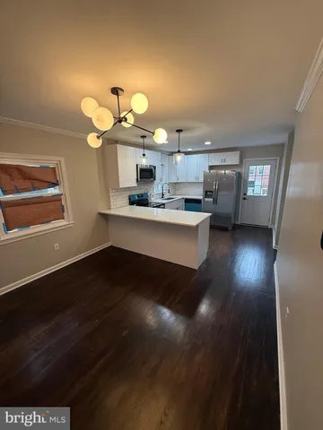 a kitchen with a sink dishwasher a dining table and chairs with wooden floor