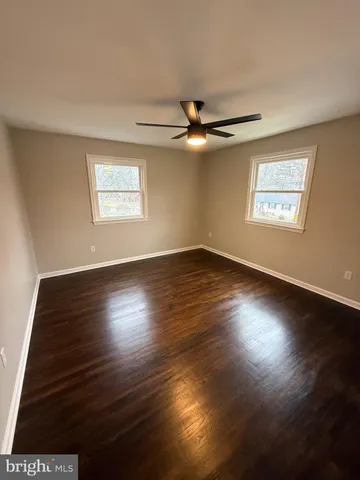 an empty room with wooden floor chandelier fan and windows