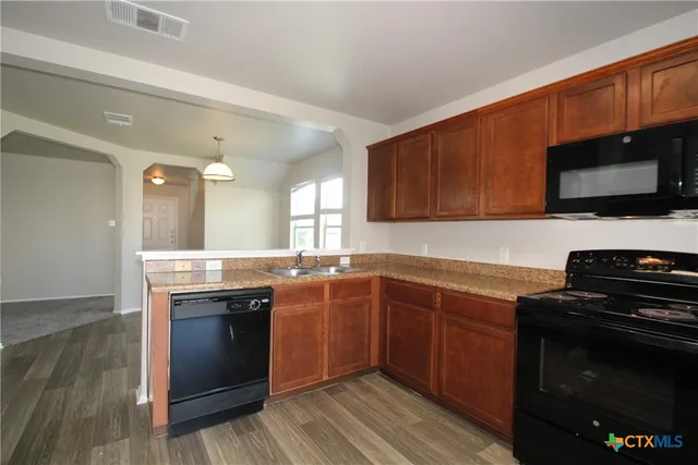 a kitchen with stainless steel appliances granite countertop wooden cabinets stove top oven and sink