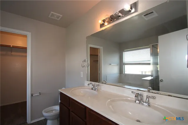 a bathroom with a granite countertop sink a toilet and a mirror