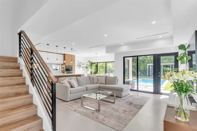 a living room with furniture and a large window with potted plants