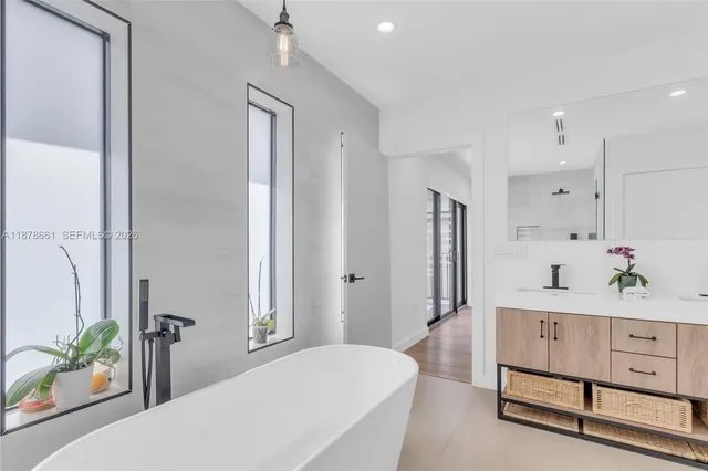 a spacious bathroom with a double vanity sink a large mirror a bathtub and a shower