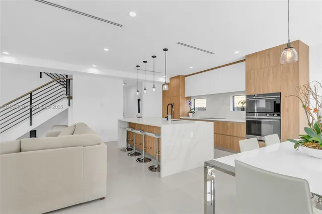 a kitchen with stainless steel appliances kitchen island a refrigerator sink and white cabinets