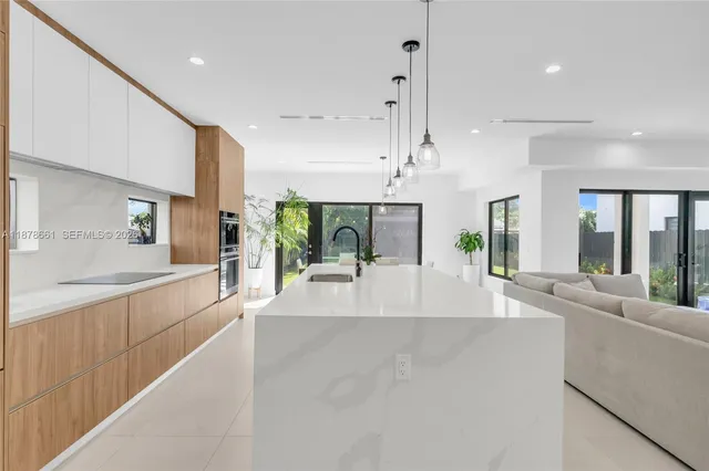 a large white kitchen with a large window and stainless steel appliances