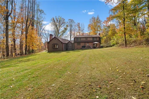 a view of a house with a big yard and large trees