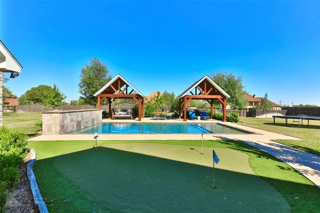 a view of swimming pool with lawn chairs and plants