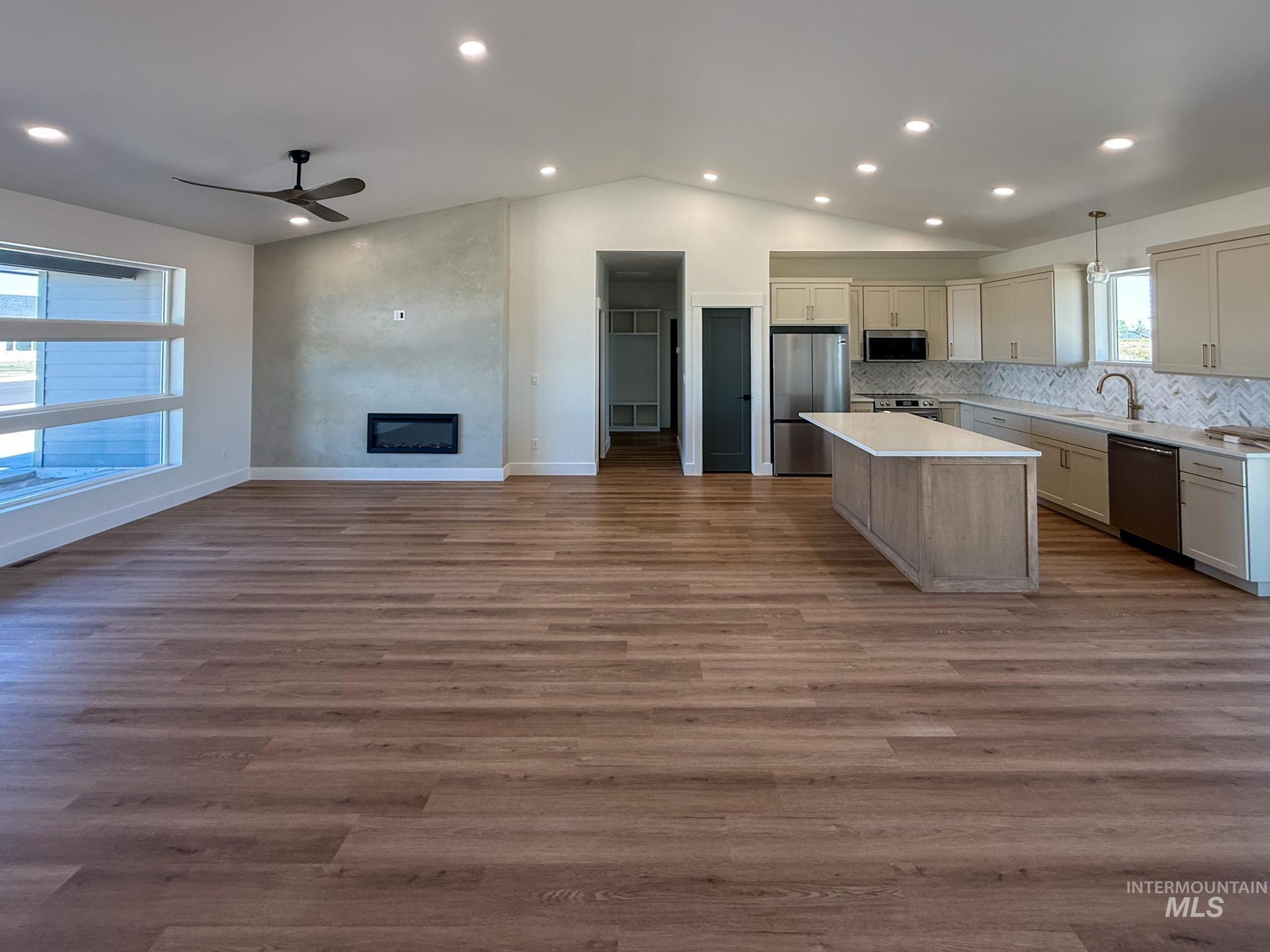 1419 Cardon Court Rupert, ID 83350 - Photo 2 of 15 Open-concept living space featuring wood-finish flooring, a contemporary linear fireplace, and vaulted ceilings with recessed lighting