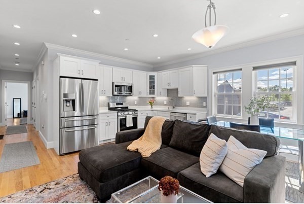 a living room with stainless steel appliances furniture a couch and a view of kitchen