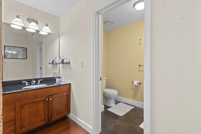 a bathroom with a granite countertop sink a toilet and a mirror