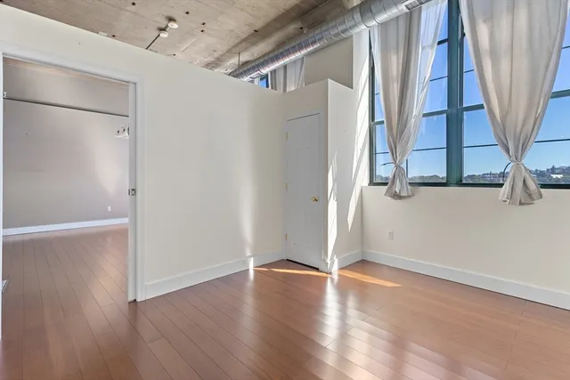 an empty room with wooden floor and entrance