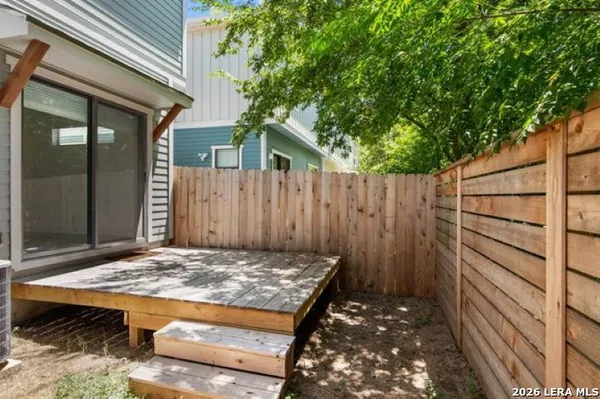 a view of a backyard with a wooden fence and a large tree