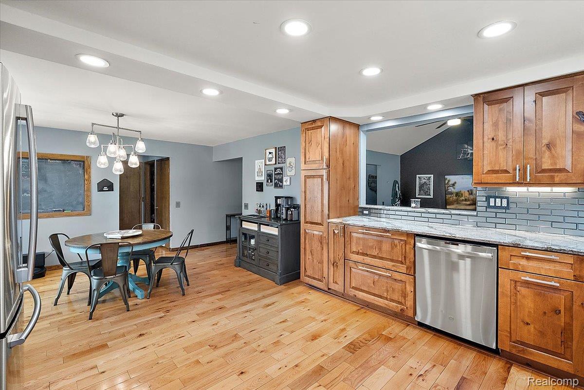 60718 Campground Road Washington, MI 48094 - Photo 17 of 37 Open-concept kitchen with wood-finish flooring, recessed lighting, wood cabinetry, stainless steel dishwasher, and a light-colored countertop