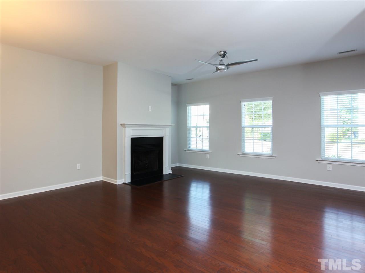 1025 Ileagnes Road Raleigh, NC 27603 - Photo 7 of 25 an empty room with wooden floor fireplace and windows