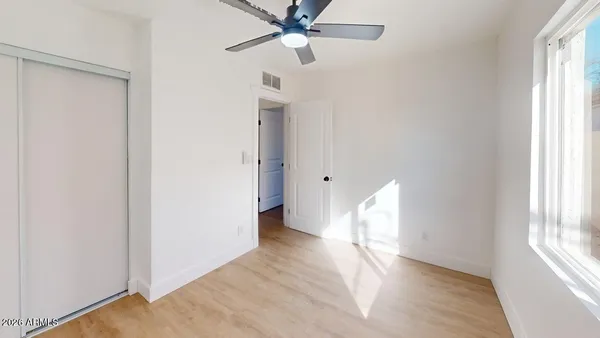 a view of empty room with wooden floor and fan
