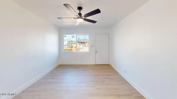 an empty room with a window and ceiling fan