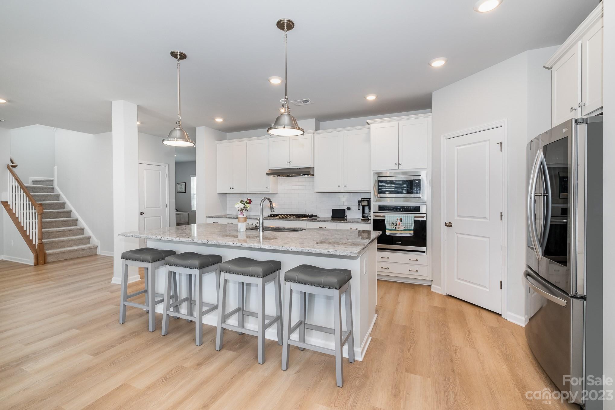 7015 Messina Road Indian Land, SC 29707 - Photo 8 of 42 a kitchen with stainless steel appliances granite countertop a refrigerator a stove top oven a sink dishwasher and a dining table with wooden floor