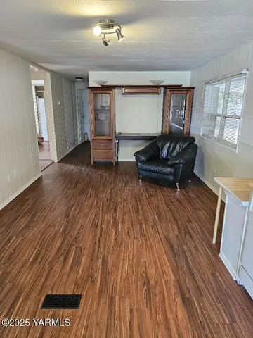 a view of an empty room with wooden floor and stairs