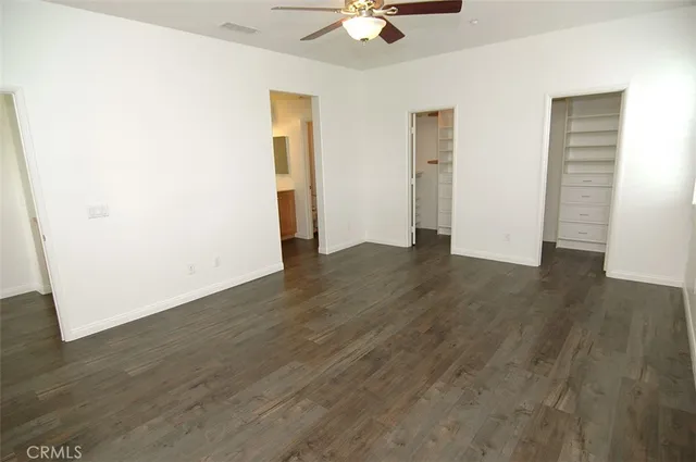 an empty room with wooden floor and ceiling fan