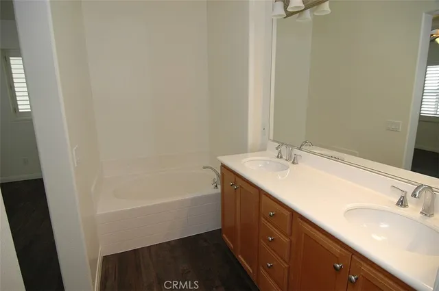 a bathroom with a tub sink double vanity and a mirror