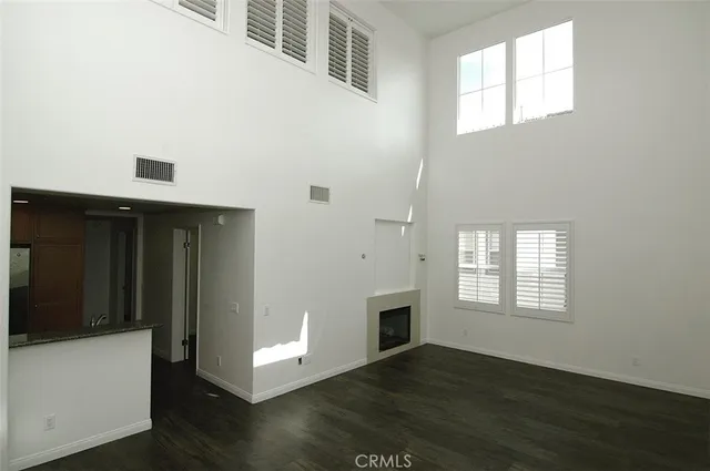 an empty room with wooden floor fireplace and windows